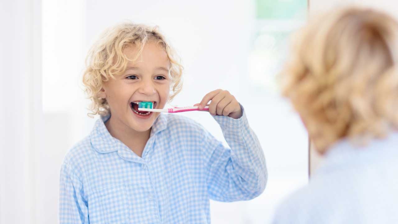 Bambino lava i denti con il dentifricio